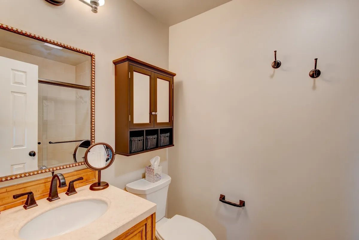 A bright, inviting bathroom with a vanity and sink, large mirror, storage cabinet, and toilet. The space is designed for comfort and relaxation, reflecting a spa-like atmosphere for unwinding.