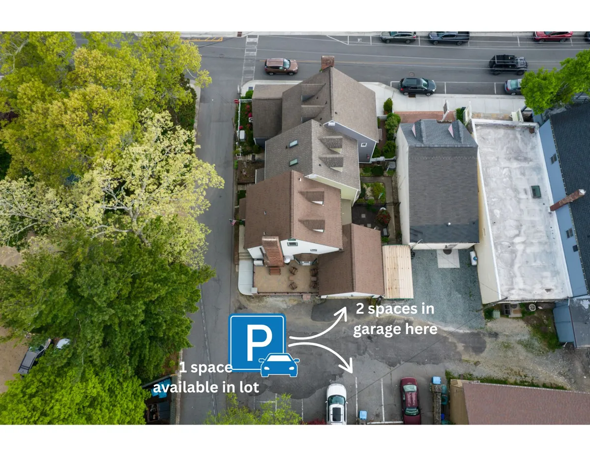 A perspective showing multiple parking spaces, the garage itself, and some of the surrounding homes. The garage is central and clearly designed for easy access, reinforcing the practical benefit of private parking and step-free entry. The setting conveys convenience and a sense of privacy for arriving guests.