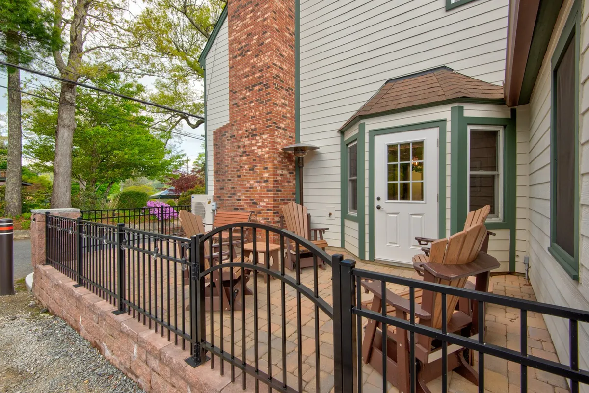 A comfortable fenced outdoor area with ample seating, a brick chimney, and an entry door, offering a safe and cozy space for group socializing and relaxation. The view suggests a private retreat within easy reach of local attractions.
