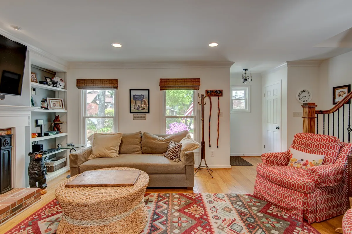 A cozy living room featuring a plush sofa, an accent chair, a coffee table, and a fireplace. Decorative items are displayed on the shelves, creating a warm, inviting atmosphere. The setup encourages relaxation, conversation, and movie nights.