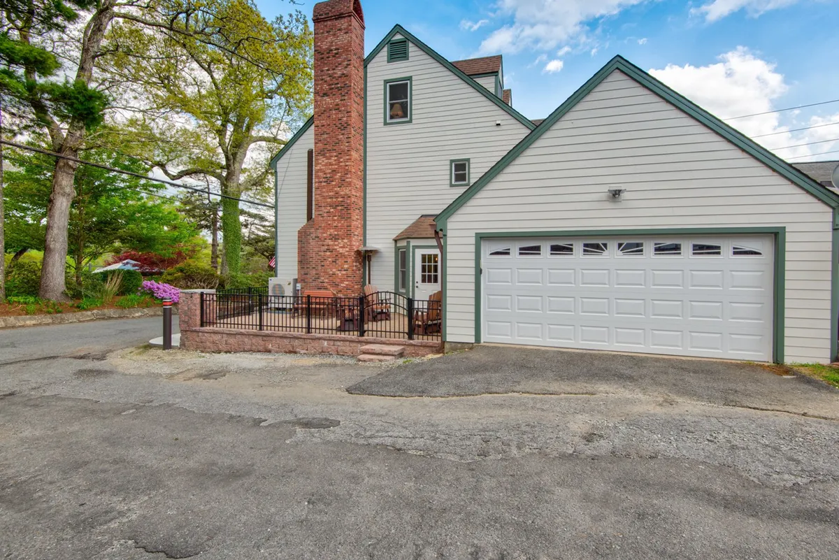 This exterior image displays the home’s brick chimney, front porch, and, crucially, the garage door. The garage is clean and easily accessible, positioned right beside the main entrance, demonstrating the zero-step transition from vehicle to entryway. The overall scene is bright, welcoming, and clearly emphasizes ease of arrival for guests.