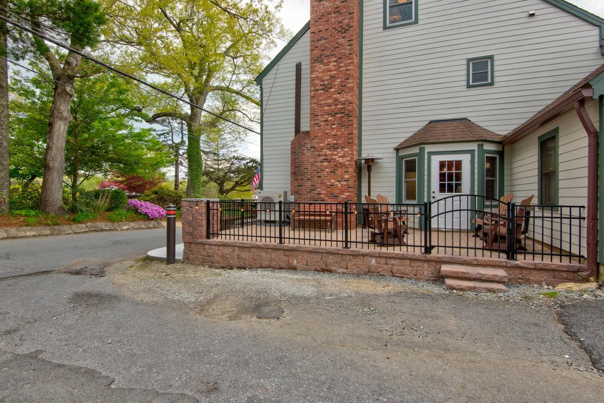 This image features a welcoming patio area bordered by greenery, a brick chimney, and comfortable outdoor seating. The scene conveys an atmosphere ideal for gathering and relaxation, with space for both adults and children to unwind after a day of adventures.